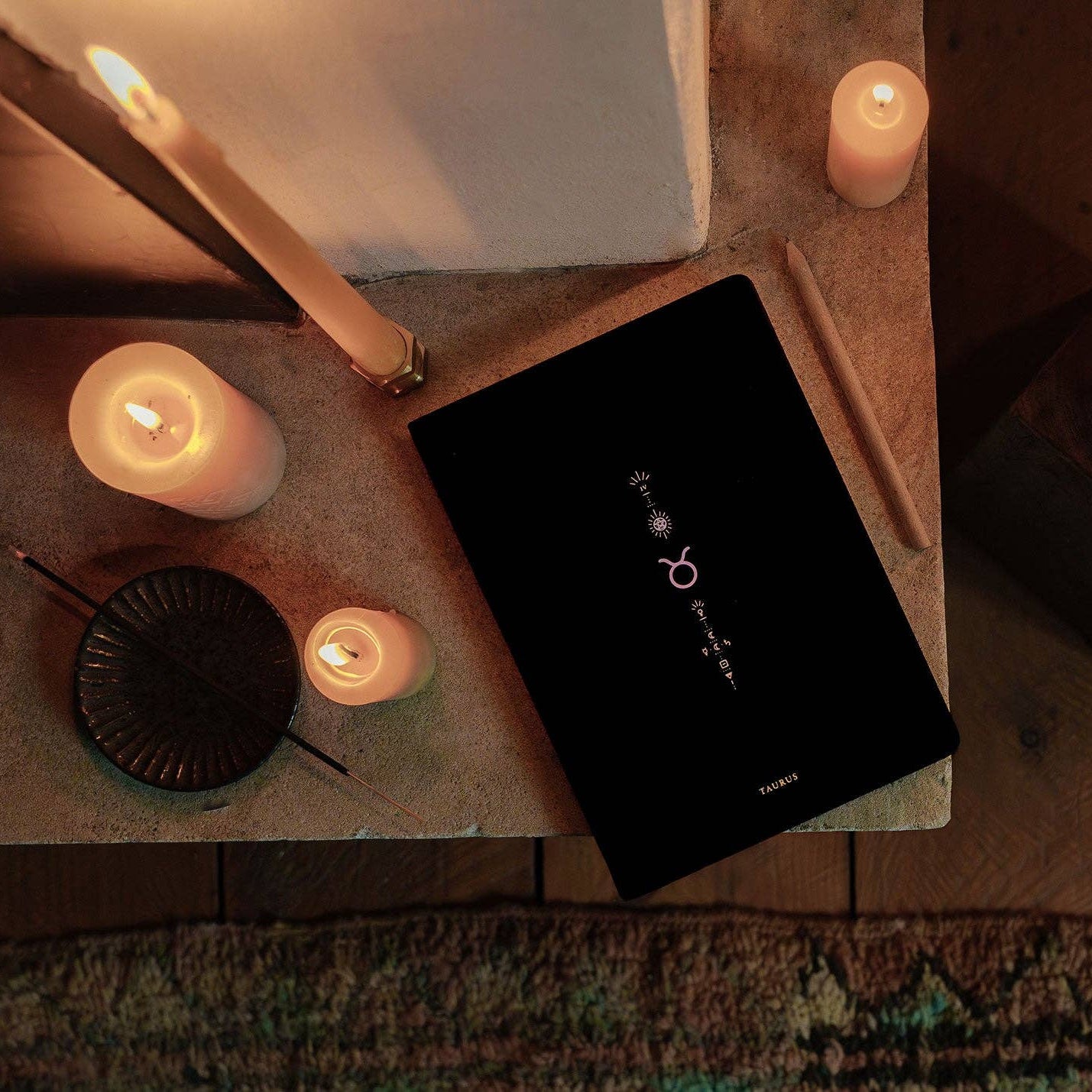 Black electronic device on a wooden surface with lit candles around it