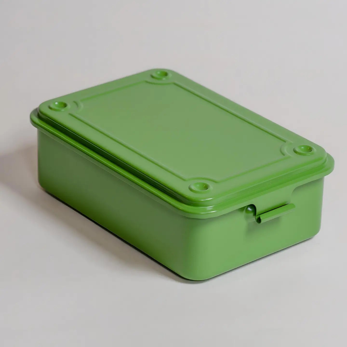 Green rectangular metal box with a lid on a light gray background
