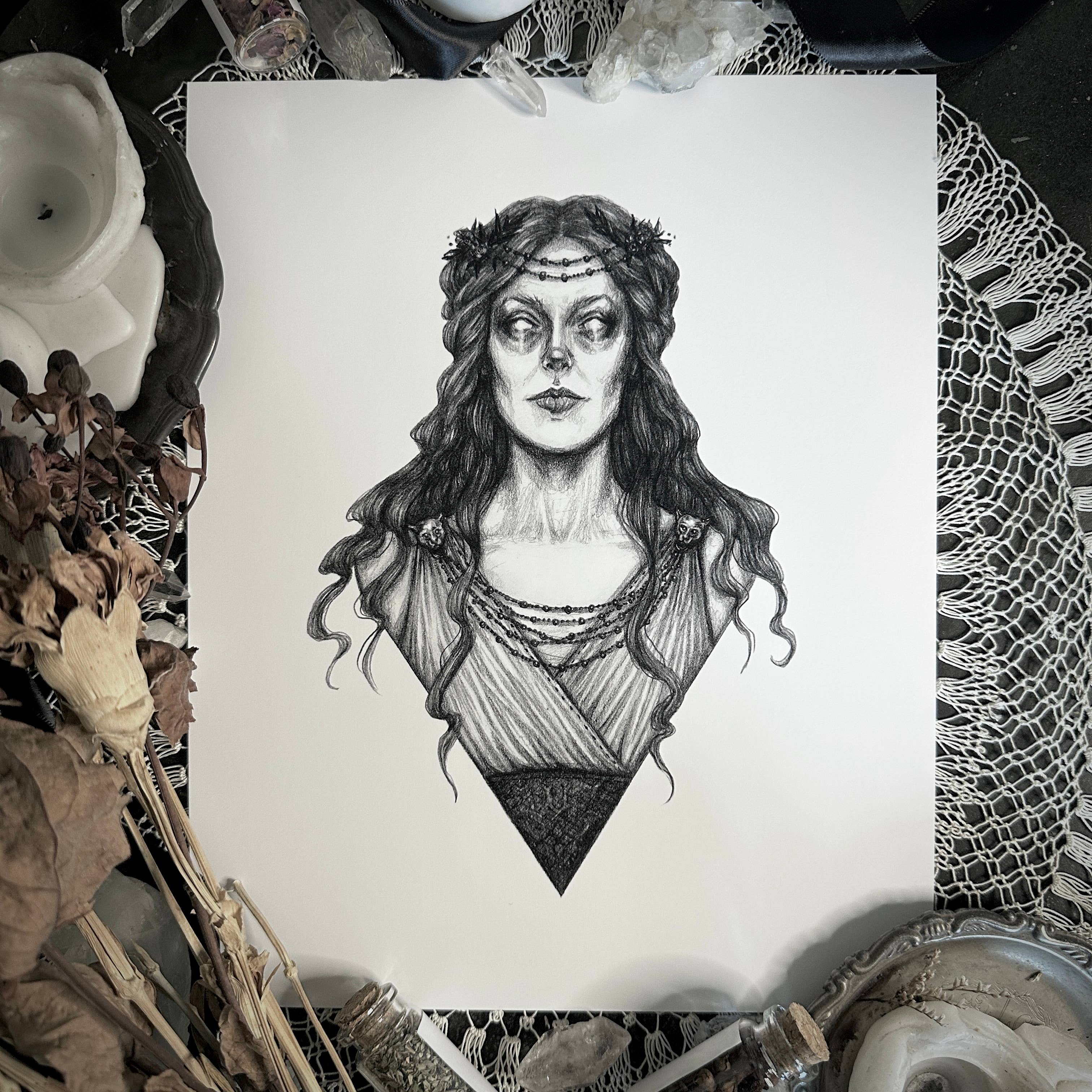 Black and white illustration of a woman's portrait on a white sheet, surrounded by decorative items.