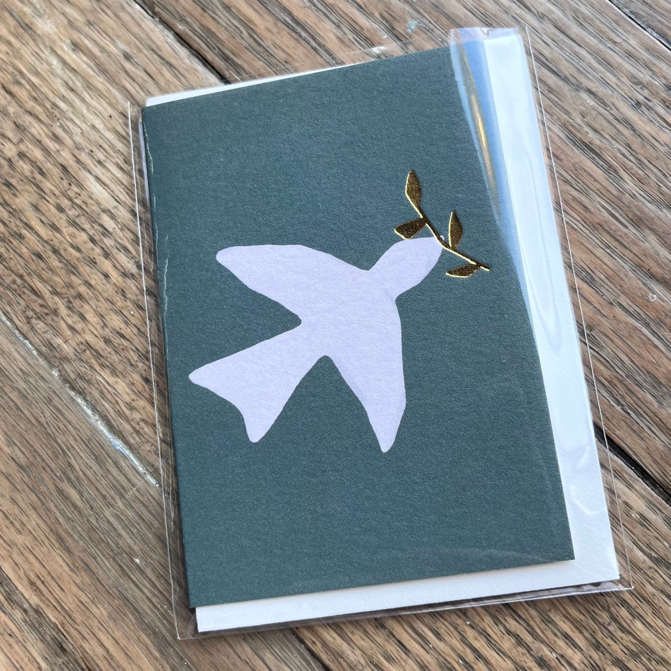 A mini dove-shaped card in a grey color with a envelope, placed on a wooden surface.