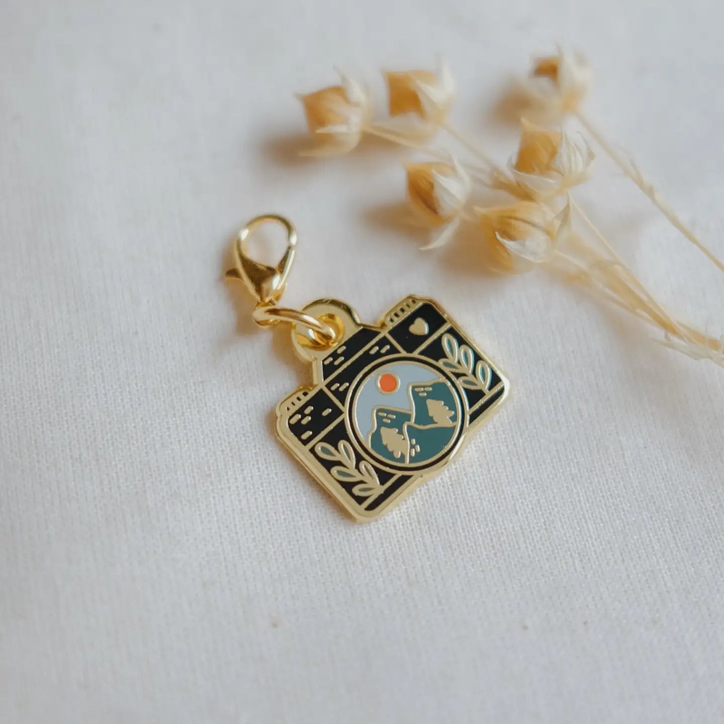 Gold charm with a camera design on a white background