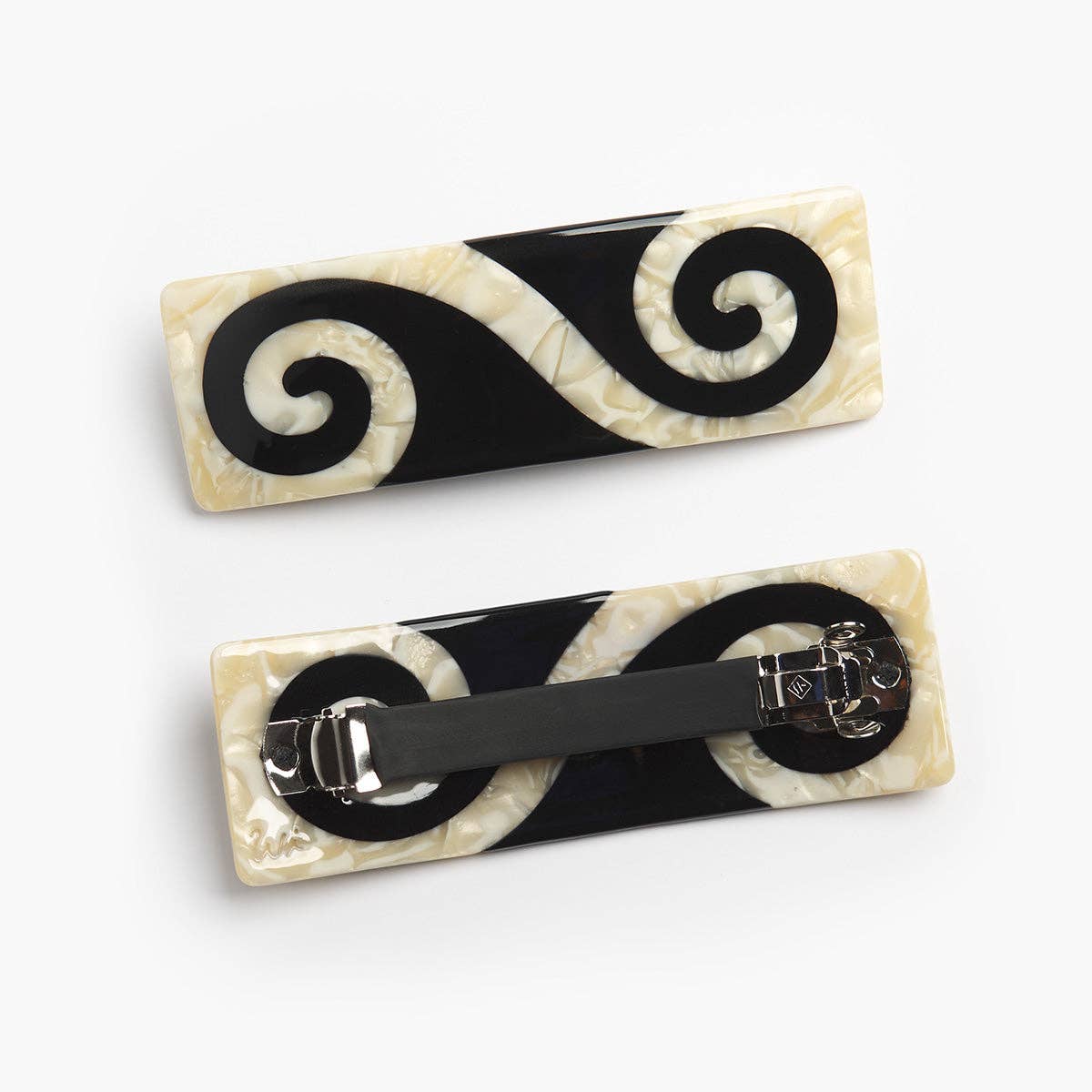 Two decorative hair clips with black and white spiral patterns on a white background