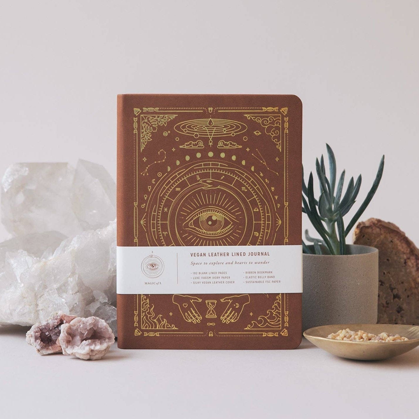 Decorative notebook with mystical design on a neutral background with plants and crystals.