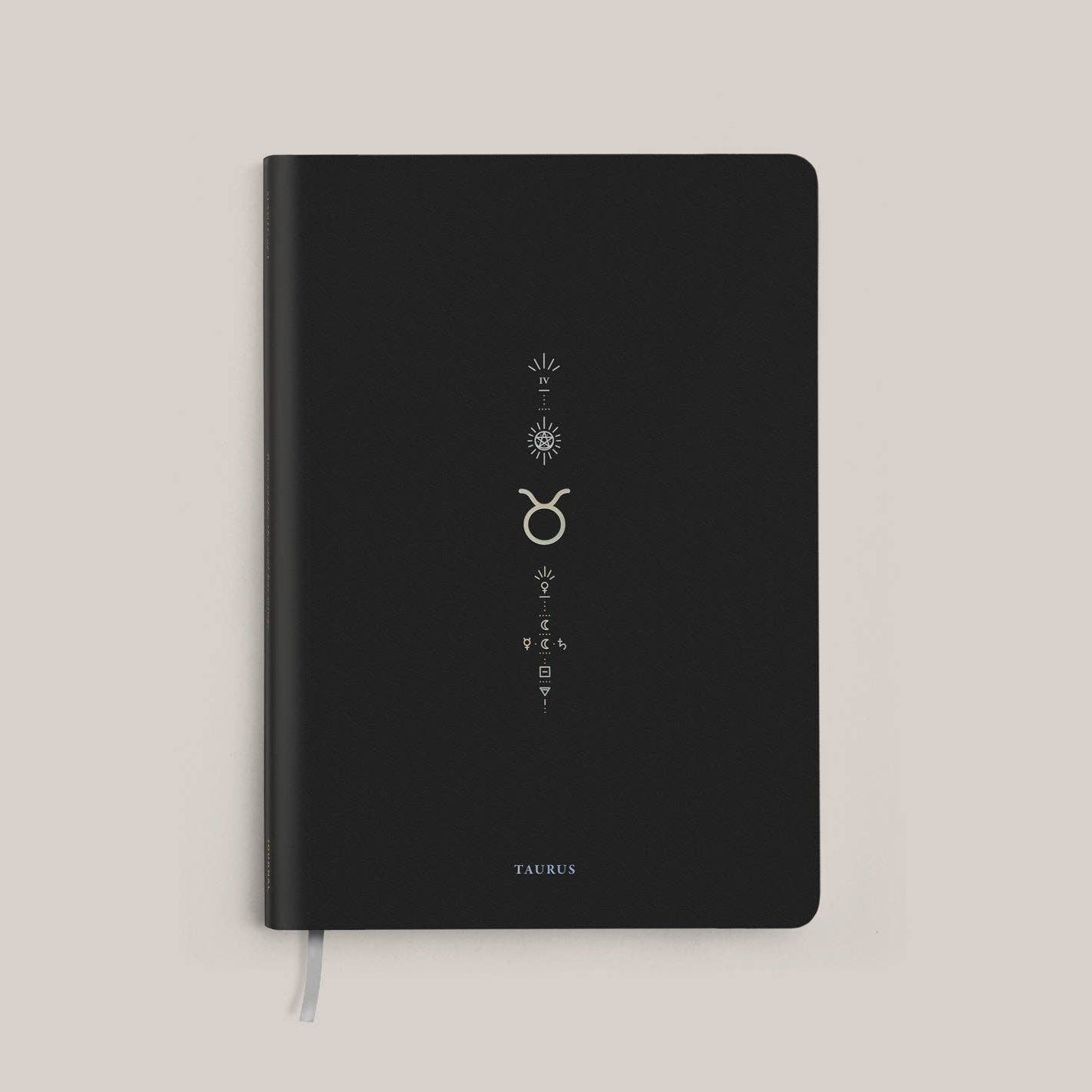 Magic of I - Black notebook with Taurus zodiac symbol on a beige background