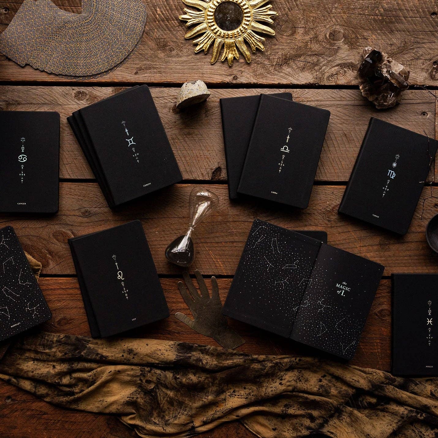 Magic of I - Zodiac Journals - Black books with star constellation designs on a wooden surface with decorative items.