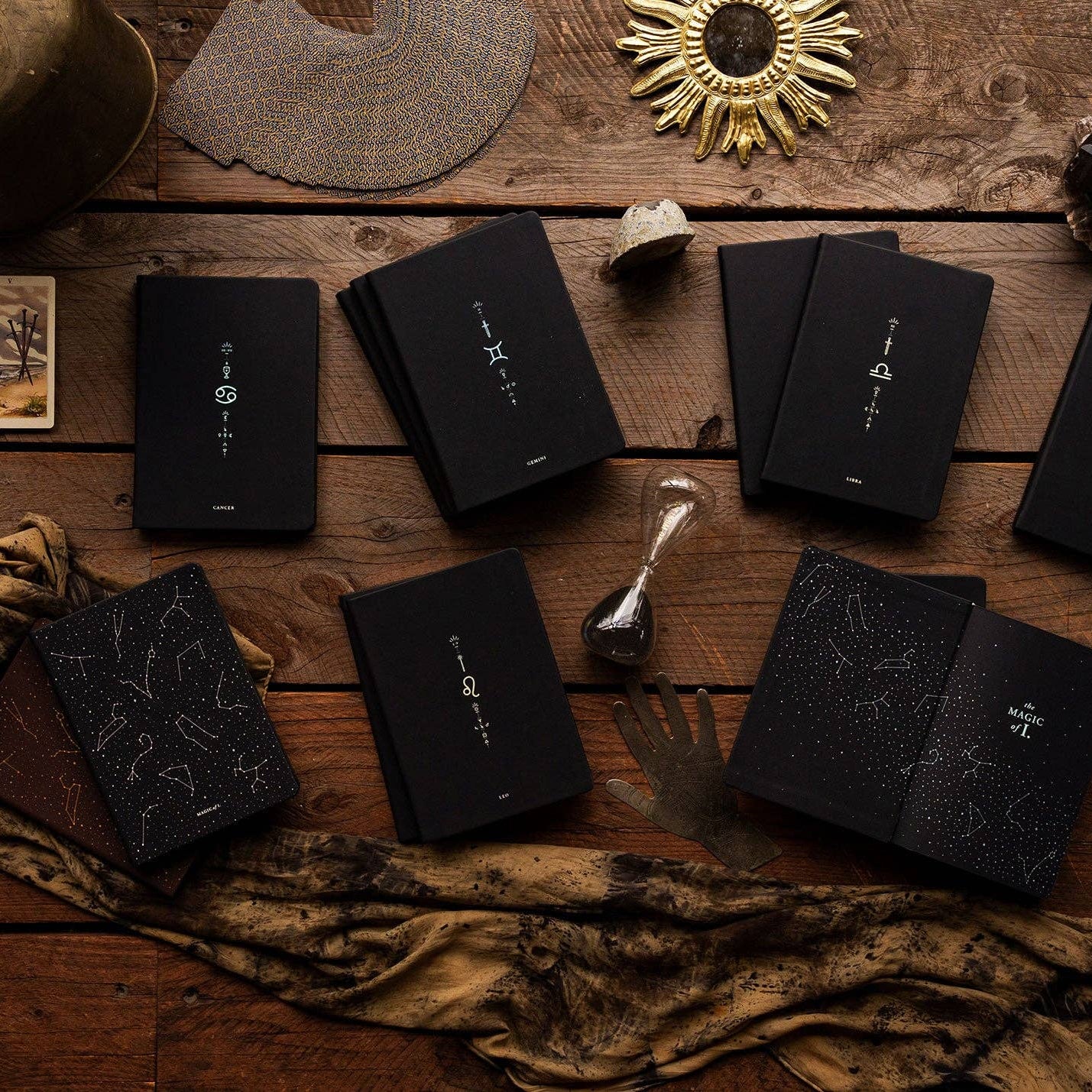 Black books with star constellation designs on a wooden surface with decorative items.