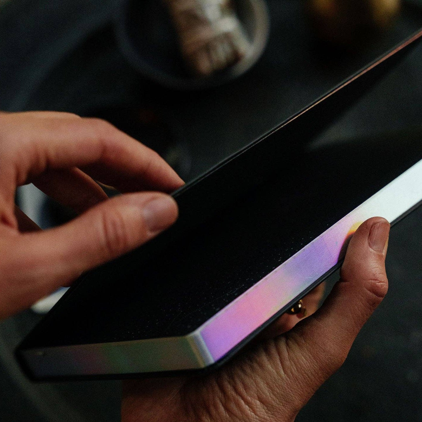Magic of I Journal - Person holding a smartphone with a reflective screen on a dark surface