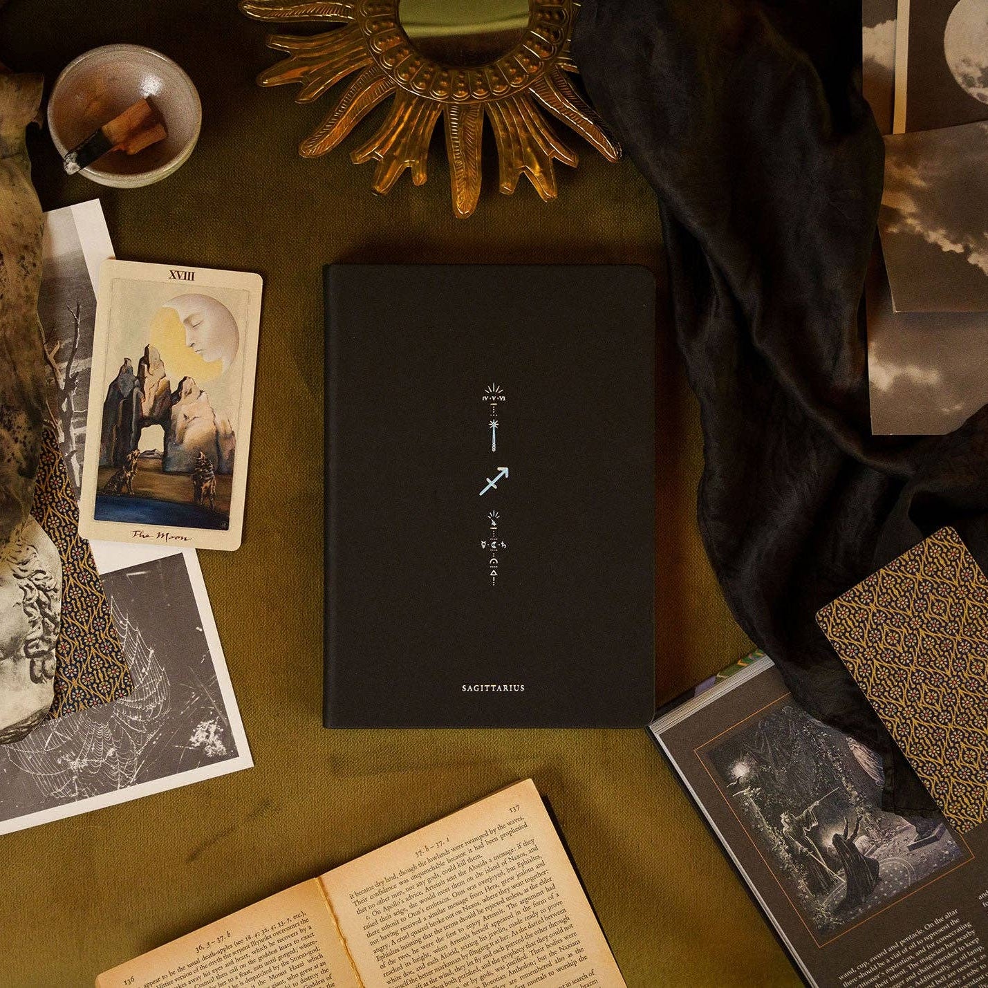 Magic of I - Zodiac Journal - Sagittarius - Dark book with celestial design on a table with vintage books and photos