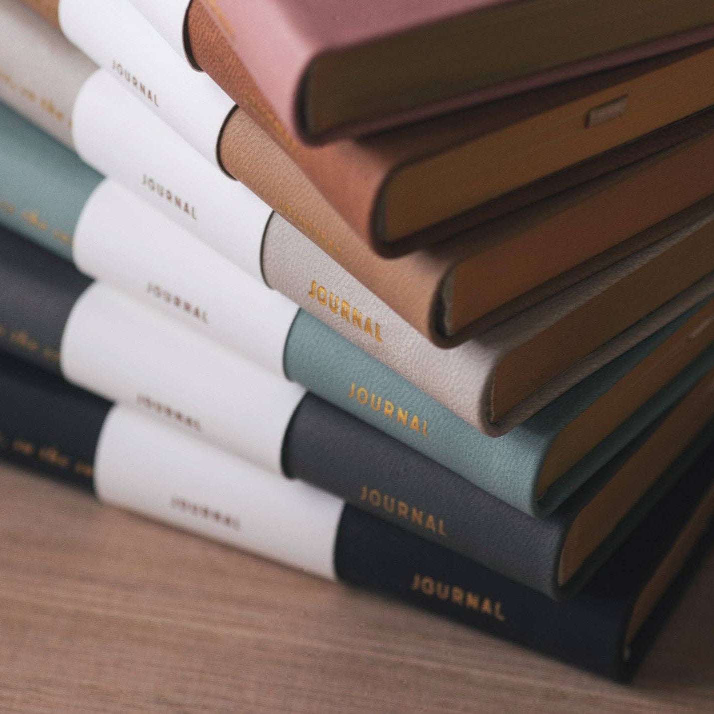 Stack of journals in various colors on a wooden surface