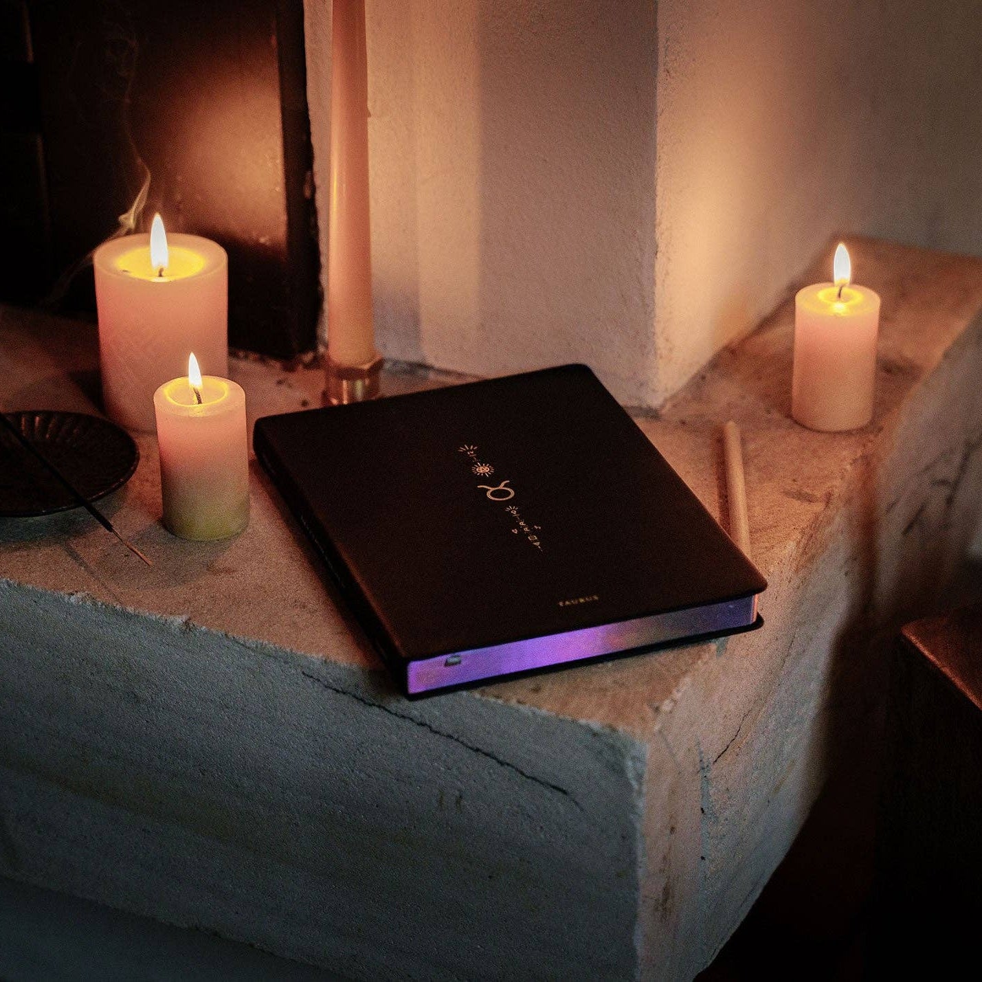 Black laptop on a stone surface with lit candles in a cozy setting