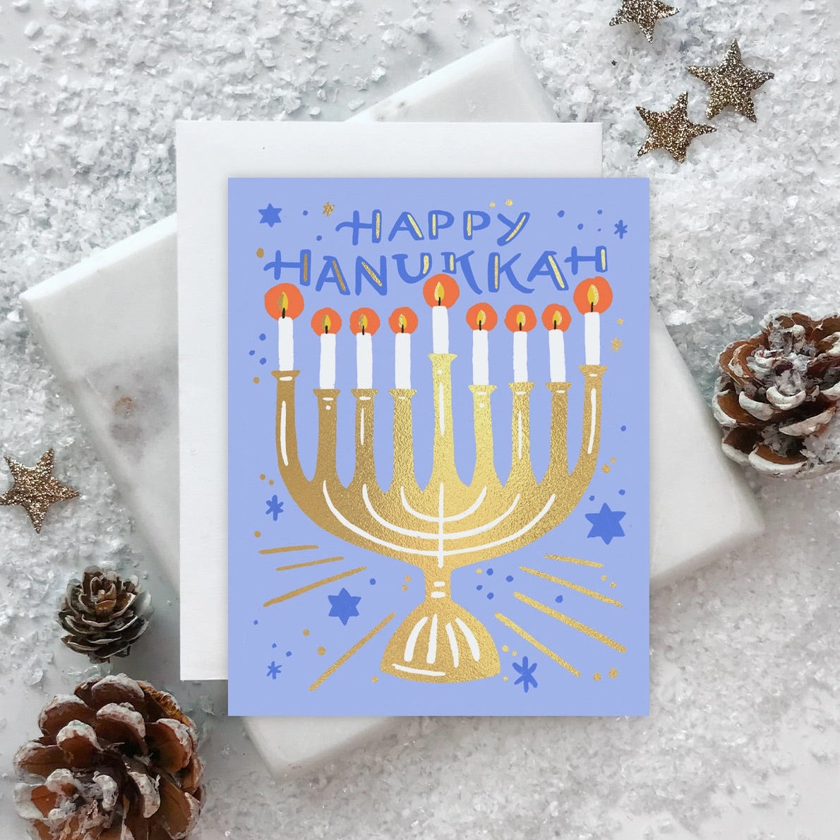 A blue greeting card with a gold menorah and stars, indicating it's a holiday card, with foil details.