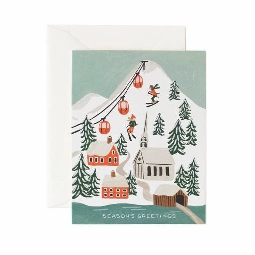 A holiday greeting card featuring a snow-covered village with a church, ski lift, and trees, and a text that reads 'Season's Greetings'.