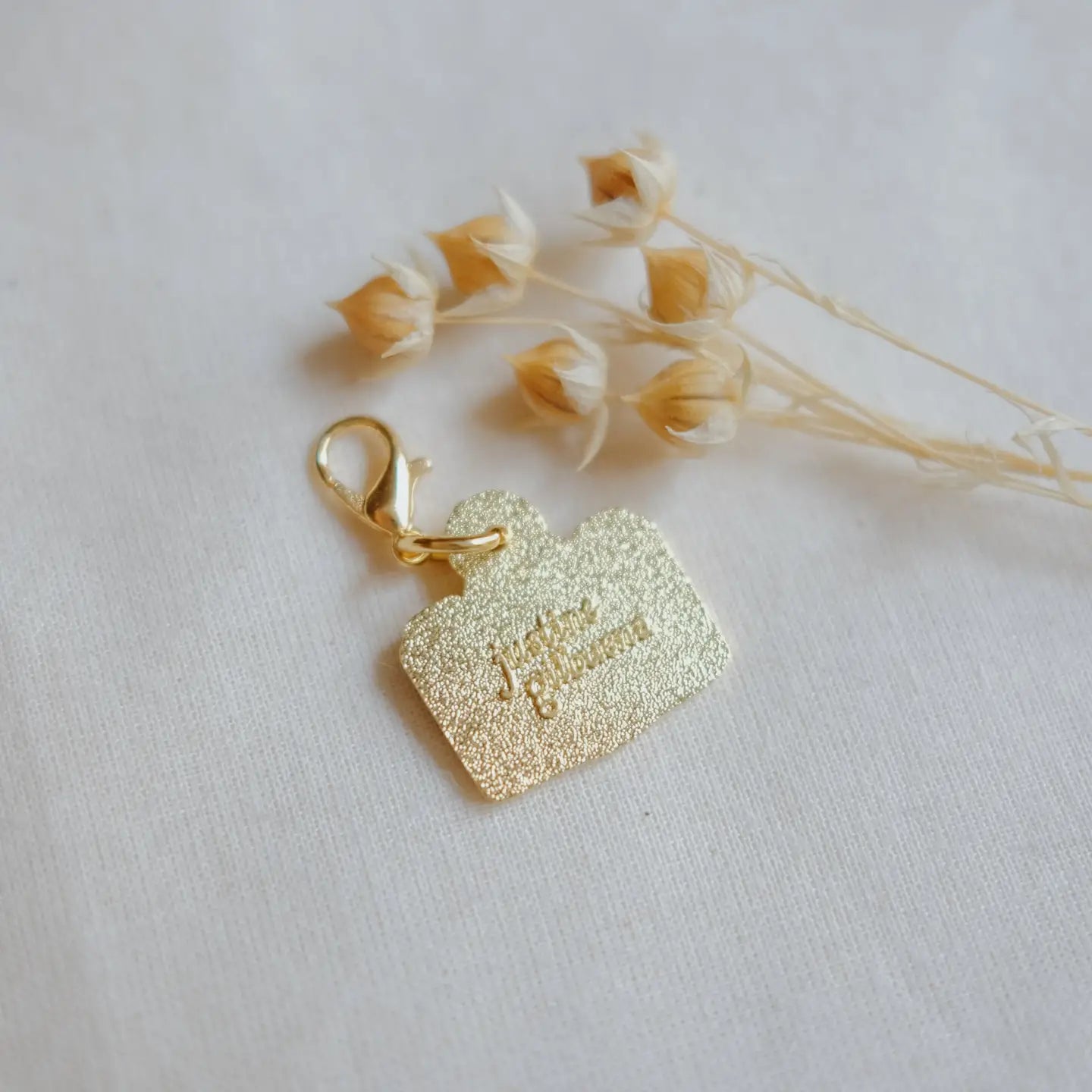 Gold glittery keychain with 'Just Married' text on a light background with dried flowers.