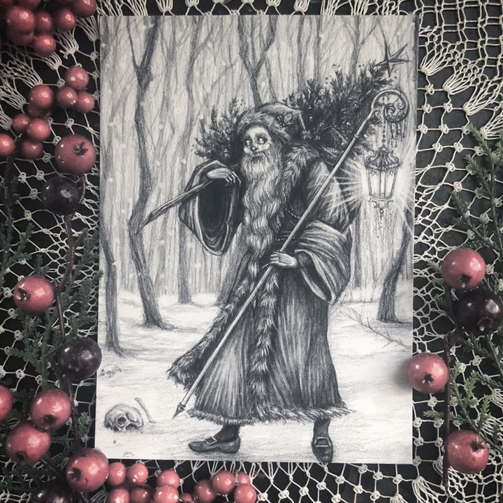 Greeting card featuring a black and white illustration of a character resembling a skeleton or a wizard, surrounded by holly and pine cones, with a black envelope included.