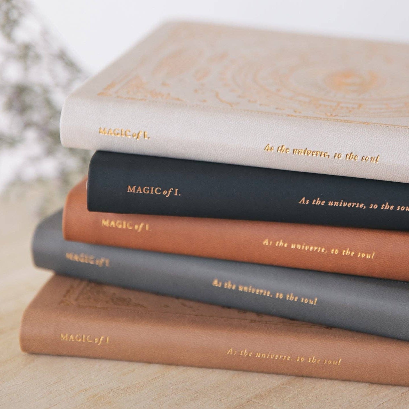 Stack of 'MAGIC OF L.' journals on a light surface with a blurred background