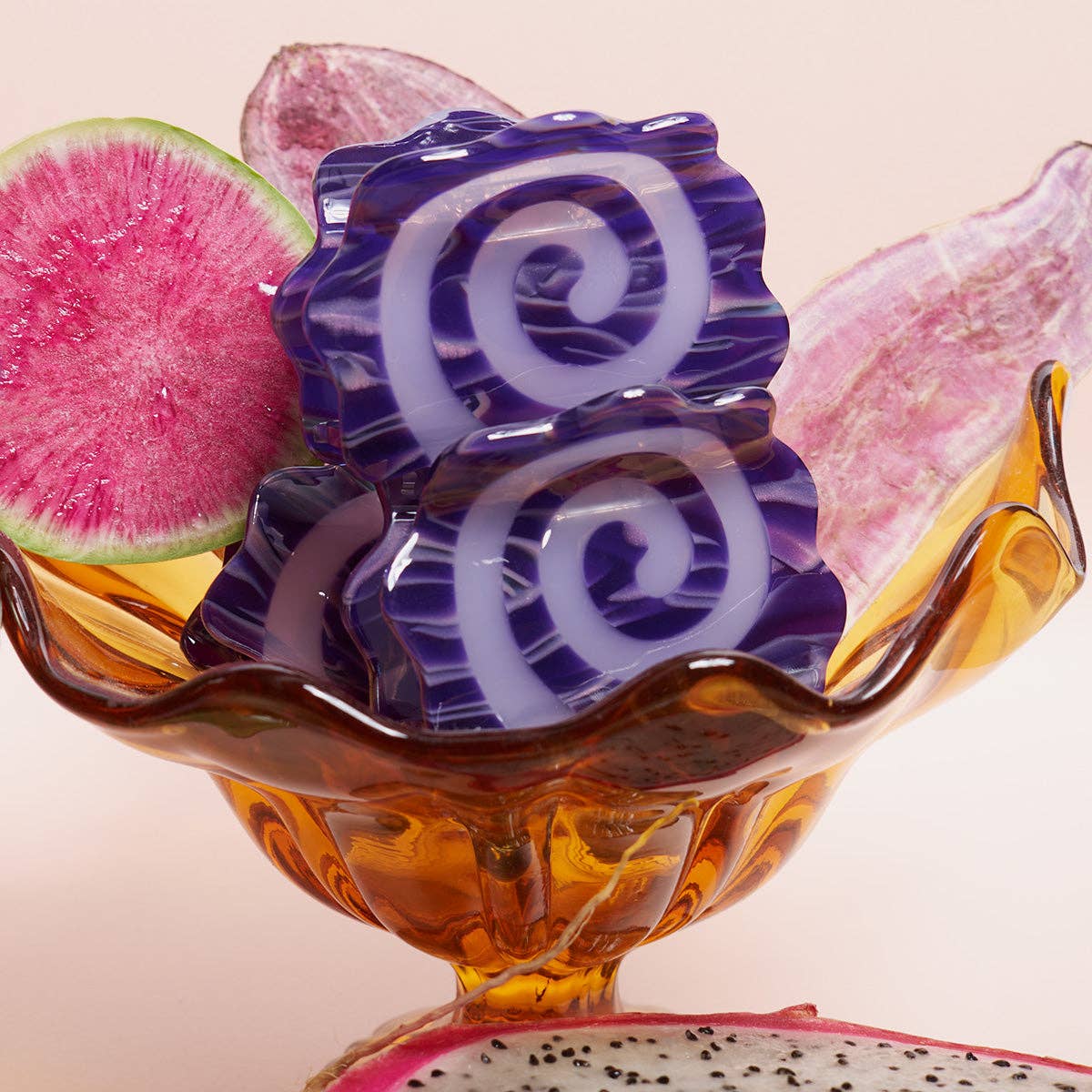 Decorative glass bowl with purple and white spiral design, surrounded by dragon fruit slices.