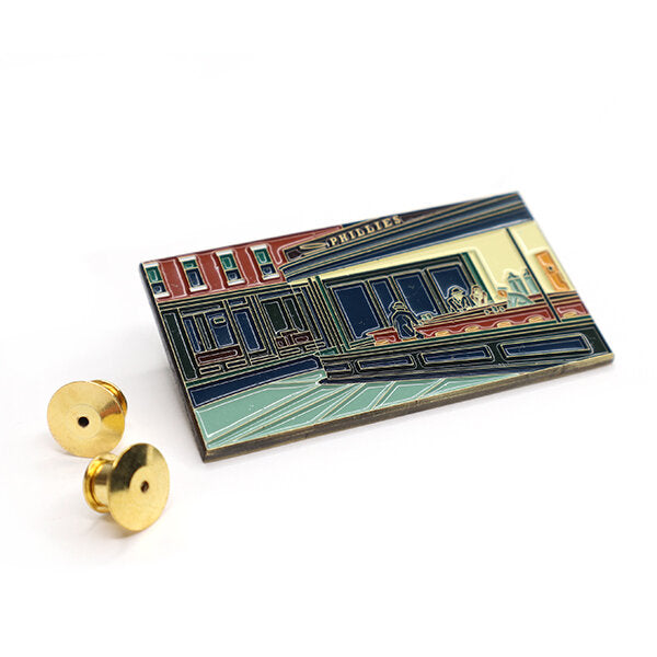 Inspired by Edward Hopper’s “Nighthawks” (1942) this large enamel pin is the perfect statement piece. Nighthawks shows customers sitting at the counter of an all-night diner. The shapes and diagonals are carefully constructed. The viewpoint is cinematic—from the sidewalk, as if the viewer were approaching the restaurant. The diner's harsh electric light sets it apart from the dark night outside, enhancing the mood and subtle emotion.
